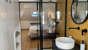 A modern bathroom with a large white sink, a mirror, and a shower area.