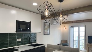 A modern kitchen with a black stove, white cabinets, and a wooden cutting board on the counter.
