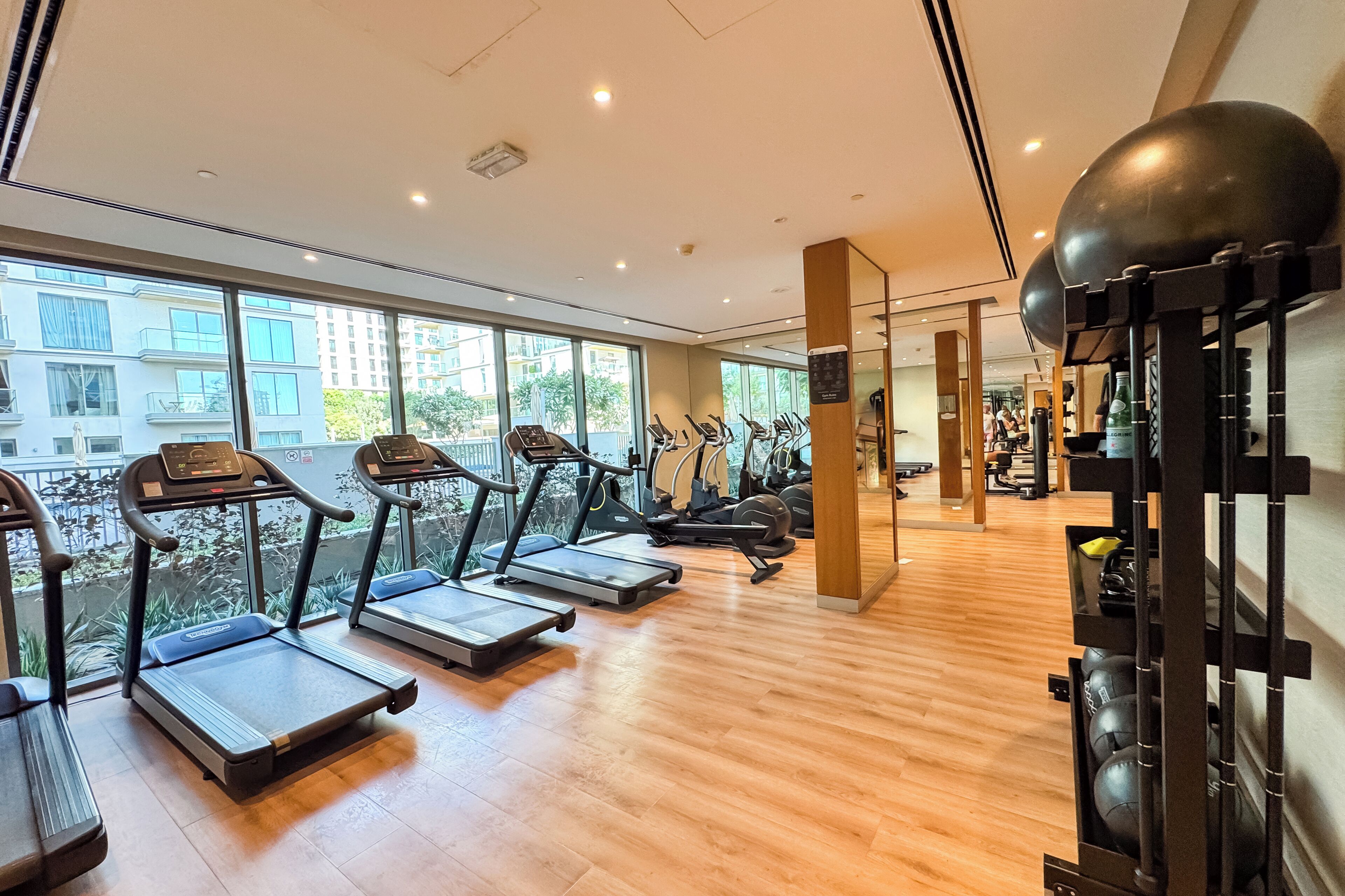 Een sportschool met loopbanden, hometrainers en een rek voor gewichten.