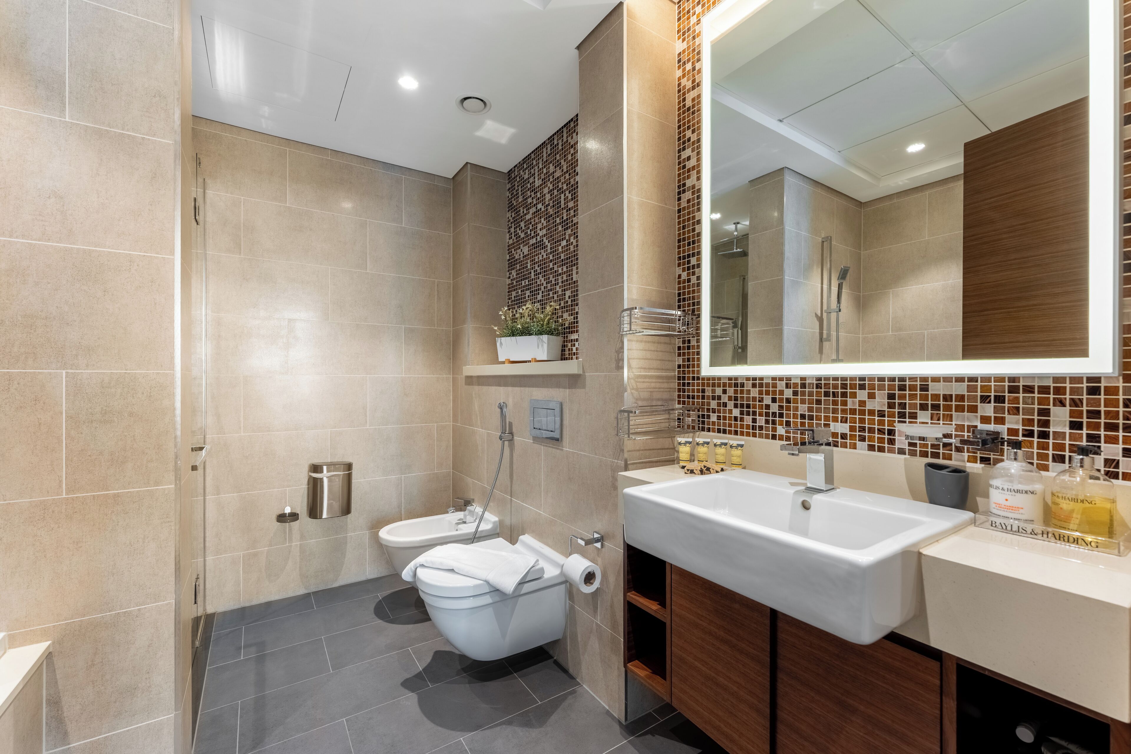 A modern bathroom with a shower, toilet, and sink.
