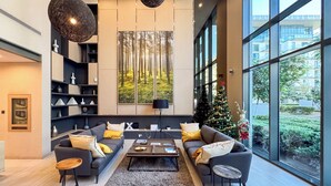 A modern living room with a large window, a fireplace, and a Christmas tree. - PVH - Serene 2BR - Sobha Hartland Greens (Dubai)