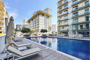 A modern hotel with a swimming pool, sun loungers, and a view of high-rise buildings. - PVH - Serene 2BR - Sobha Hartland Greens (Dubai)