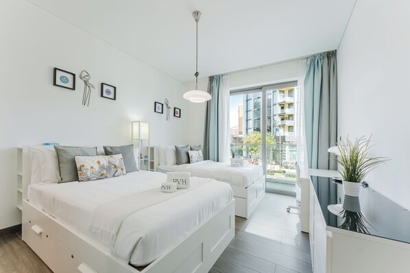 A modern hotel room with two beds, a desk, a balcony, and city views. - PVH - Serene 2BR - Sobha Hartland Greens (Dubai)