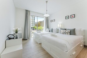 Et moderne hotelværelse med stort vindue, to senge, et skrivebord og en lille plante.
