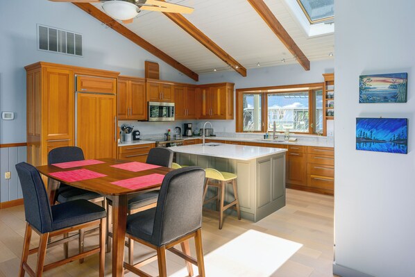 A modern kitchen with wooden cabinets, a large island, and a dining area with chairs.
