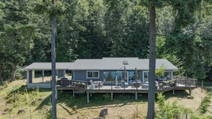 Une maison moderne dotée d’une terrasse, entourée d’une forêt dense.