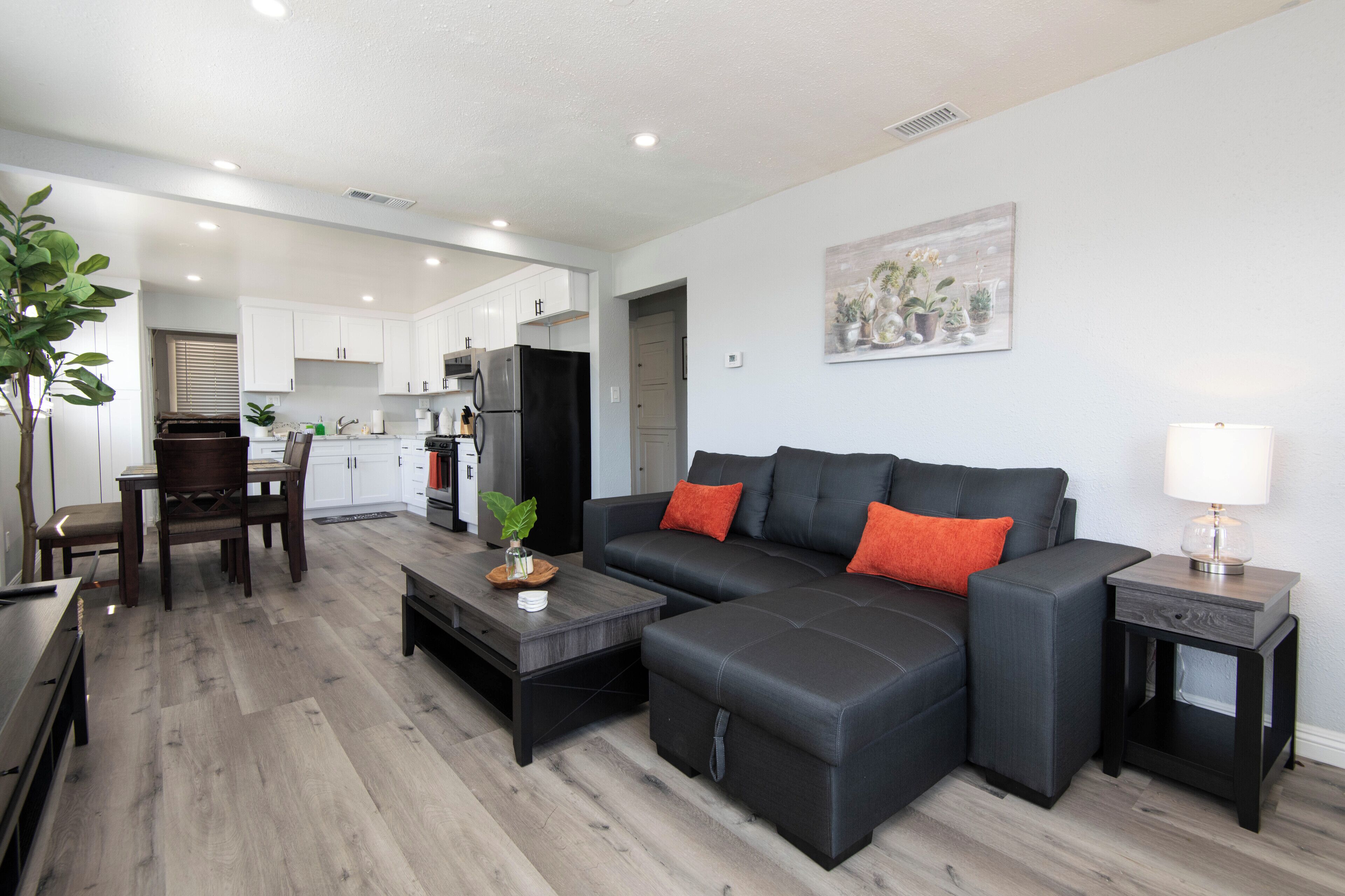 A modern living room with a sectional sofa, a coffee table, and a dining area with a table and chairs.