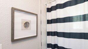 A framed picture on a wall next to a striped shower curtain.