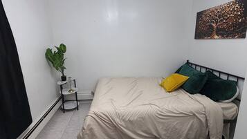 Ein Schlafzimmer mit einem Bett, einer Pflanze, einem Bild und einer Deckenleuchte.