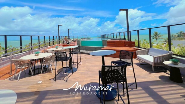 Une terrasse sur le toit avec des sièges extérieurs, une piscine et une vue sur l’océan.