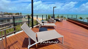 Une terrasse avec des chaises longues et vue sur l’océan.