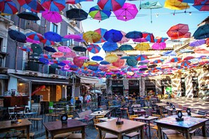 An outdoor café area with tables and chairs, surrounded by colorful umbrellas. - Dimora Di Nardo, Zagara Apartment, front Ursino Castle in the heart of Catania (Catania)
