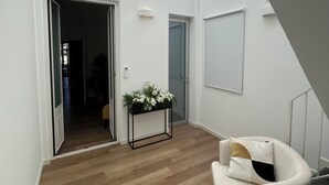 A spacious room with a high ceiling, a white chair, a small table with flowers, and a view of a hallway. - Dimora Di Nardo, Zagara Apartment, front Ursino Castle in the heart of Catania (Catania)