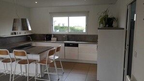 Een moderne keuken met een centraal eiland, witte kasten en een raam voor natuurlijk licht.