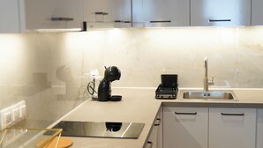 A modern kitchen with white cabinets, a stainless steel sink, and a built-in oven.