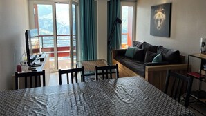 A modern hotel room with a balcony, a dining area, a sofa, and a bed.