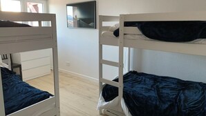 A room with two bunk beds, a white wall, a window, and a mounted picture.