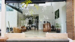 A modern building entrance with a glass door, a wooden bench, and a small table with a basket. - Beautiful apartment 10 minutes from the beach with Jacuzzi Swimming pools GYM Terraces. (TULUM)