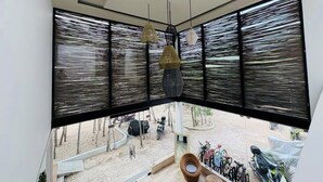 A modern room with large windows, a ceiling fan, and hanging pendant lights. - Beautiful apartment 10 minutes from the beach with Jacuzzi Swimming pools GYM Terraces. (TULUM)