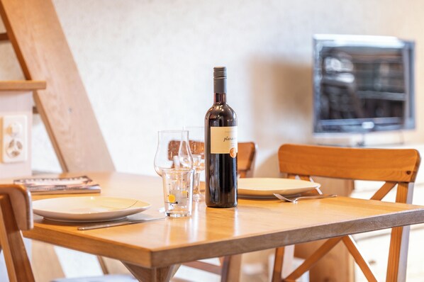 A dining table with a bottle of wine, glasses, and a plate.