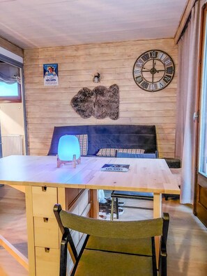A cozy room with a wooden wall, a large clock, a poster, and a unique rug. - 20m from resort center, 3rd floor, balcony, parking, ski locker, 24m², Les Gets (Les Gets)
