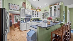 A modern kitchen with white cabinets, a large island, and a dining area with wooden chairs.