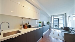 Una cocina moderna con un lavamanos empotrado, armarios oscuros y un amplio ventanal con vistas a un balcón.