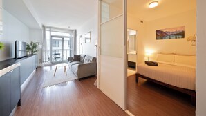 Un apartamento moderno con cocina, sala de estar y dormitorio. Cuenta con una puerta corrediza, un sofá, una cama y un cuadro en la pared.