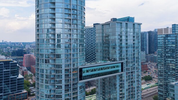 Un edificio de gran altura con fachada de vidrio moderna, rodeado de otros edificios altos en un entorno urbano.