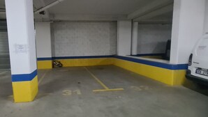 Un garaje de estacionamiento con paredes blancas y amarillas, piso de concreto y una motocicleta estacionada en una esquina.