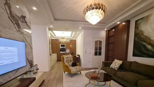 Una sala de estar moderna con televisor, una mesa de centro redonda, un sofá y un sillón estampado.