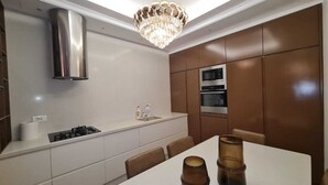 Una cocina moderna con encimera blanca, electrodomésticos de acero inoxidable y una lámpara de araña.