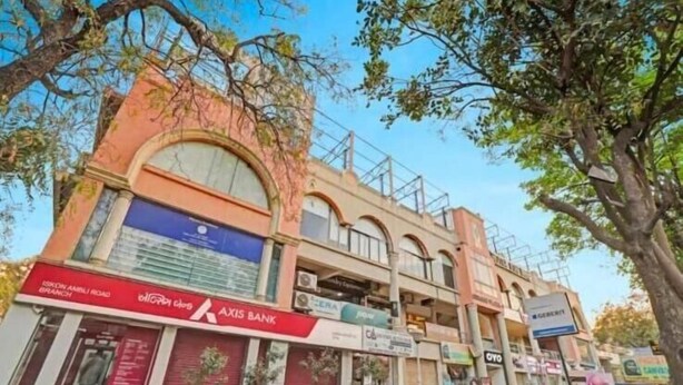 A multi-story building with various commercial establishments, including a bank and a bookstore. - hotel stay inn bopal (Ahmedabad)