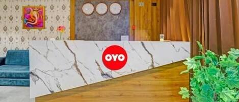 A reception area with a marble counter, a blue sofa, a wall clock, and a wooden panel.