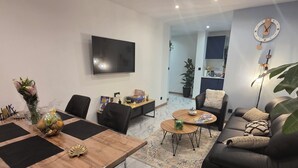 Un salon moderne comprenant un coin repas, un canapé, un téléviseur et une plante en pot.