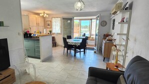 A compact living space with a TV, sofa, dining table, and kitchenette. - Nice 2P with Wifi & swimming pool near city center (Fréjus)