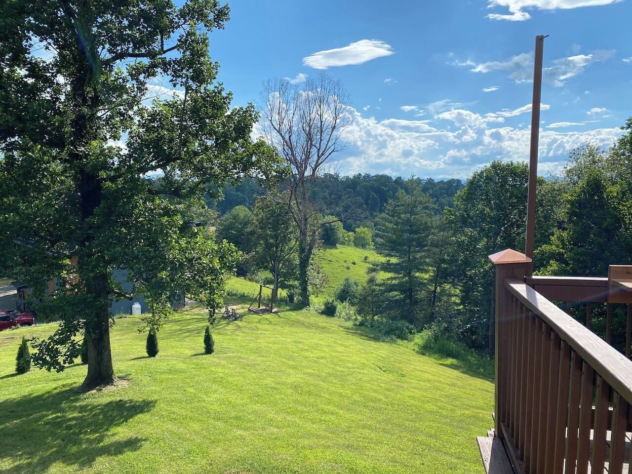 A grassy landscape with trees and a wooden deck.