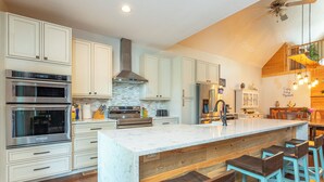 Una cocina moderna con armarios blancos, electrodomésticos de acero inoxidable y una isla grande con taburetes de bar.