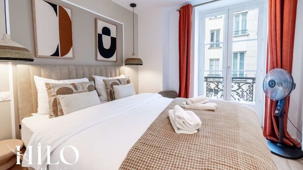 Habitación de hotel con una cama grande, vistas a la ciudad y un balcón con barandilla.