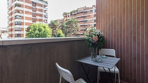 A balcony with a table and chairs, a vase of flowers, and a view of residential buildings.