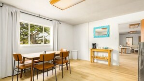 Un espace repas moderne avec une table et des chaises en bois, un coin café et une vue sur l’extérieur.