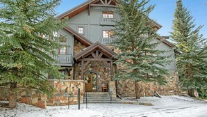 A multi-story lodge with a stone facade, wooden trim, and a prominent entrance with a wooden door.