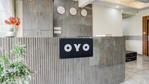 Ένας πάγκος υποδοχής με μια πινακίδα που γράφει «OYO» και τρία ρολόγια τοποθετημένα από πάνω.