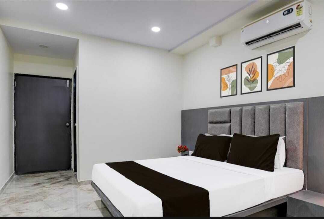 Una camera d'albergo moderna con un letto, un comodino, un condizionatore d'aria a parete e tre quadri incorniciati.