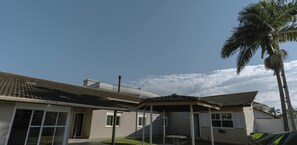 A residential building with a tiled roof, a covered patio, and a palm tree. - Casa espaçosa a 200m da Praia em Florianópolis (Florianópolis)