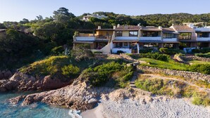 A coastal property with multiple buildings, a rocky shoreline, and a clear view of the sea.