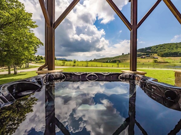A hot tub with a view of a green landscape and hills.