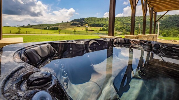 Un bain à remous offrant une vue dégagée sur un paysage verdoyant et des collines en arrière-plan.