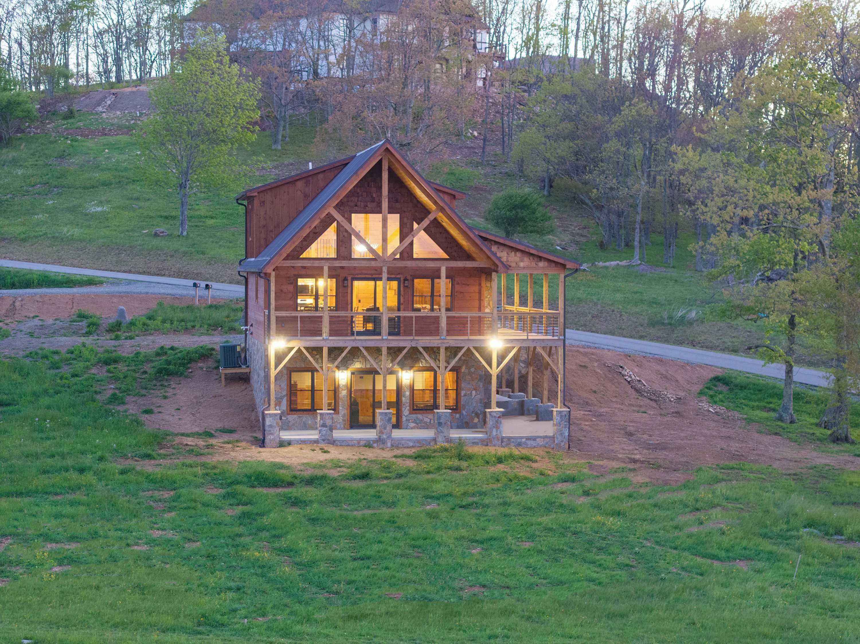 A large wooden cabin with a stone foundation, multiple windows, and a balcony.