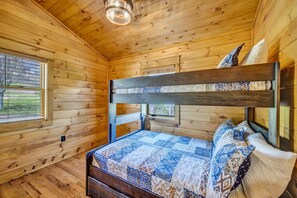 A wooden cabin bedroom with a bunk bed, a window with blinds, and a ceiling light fixture. - Brand New | Hot Tub + Grandfather Mtn + Views (Banner Elk)